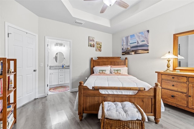 14214 NW 154th Pl, Alachua, FL 32615 - bedroom featuring a tray ceiling, light wood finished floors, ensuite bath, and ceiling fan