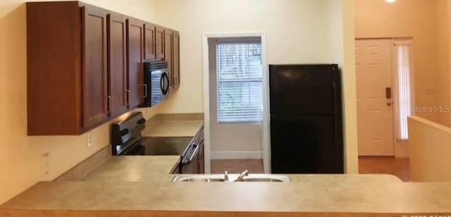 2915 SW 35th Pl Unit 102, Gainesville, FL 32608 - kitchen featuring range with electric cooktop, black microwave, a sink, and light countertops
