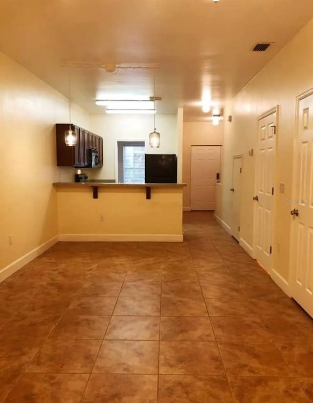 2915 SW 35th Pl Unit 102, Gainesville, FL 32608 - kitchen with fridge, tile patterned flooring, a breakfast bar area, a peninsula, and pendant lighting