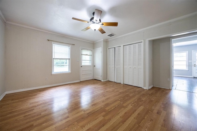 1404 NW 10th Ave, Gainesville, FL 32605 - unfurnished bedroom featuring wood finished floors, multiple closets, ornamental molding, and ceiling fan