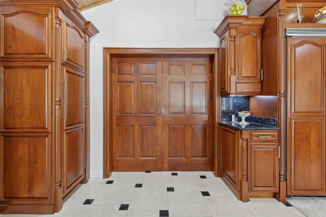 518 SW Little Rd, Lake City, FL 32024 - kitchen featuring brown cabinetry, dark stone counters, light tile patterned floors, and backsplash