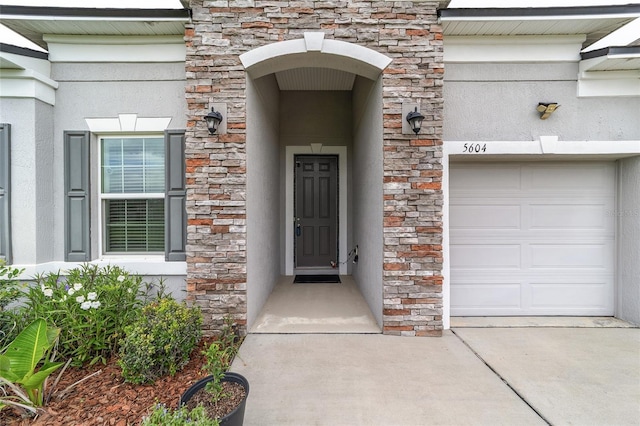 5604 SW 215th Ter, Newberry, FL 32669 - view of exterior entry featuring stone siding, a garage, and stucco siding