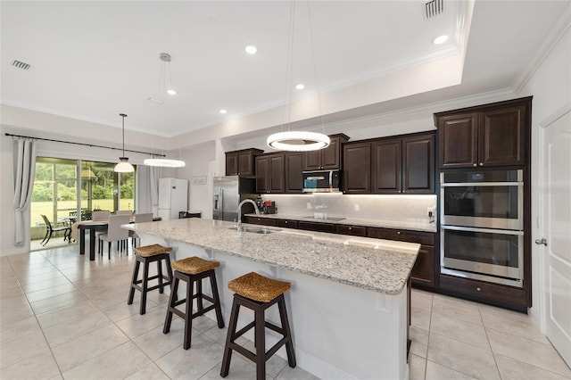 5604 SW 215th Ter, Newberry, FL 32669 - kitchen with stainless steel appliances, light tile patterned floors, a kitchen bar, dark brown cabinetry, and a spacious island