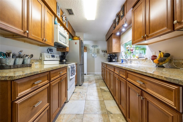 261 Ishie Ave, Bronson, FL 32621 - kitchen with white appliances, brown cabinetry, light stone counters, and a textured ceiling