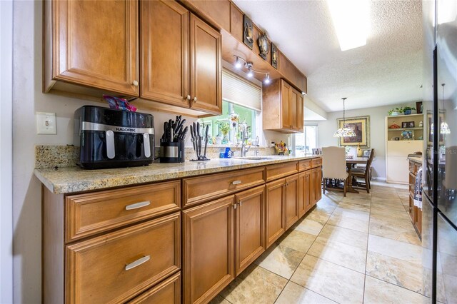261 Ishie Ave, Bronson, FL 32621 - kitchen featuring brown cabinetry, a textured ceiling, pendant lighting, and light stone countertops