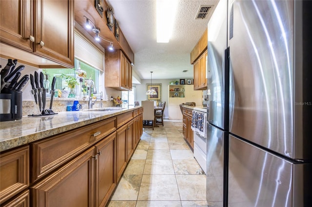 261 Ishie Ave, Bronson, FL 32621 - kitchen with freestanding refrigerator, brown cabinetry, a textured ceiling, pendant lighting, and white stove