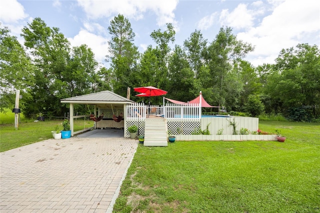 261 Ishie Ave, Bronson, FL 32621 - view of grassy yard with a carport, an outdoor pool, a wooden deck, view of scattered trees, and decorative driveway