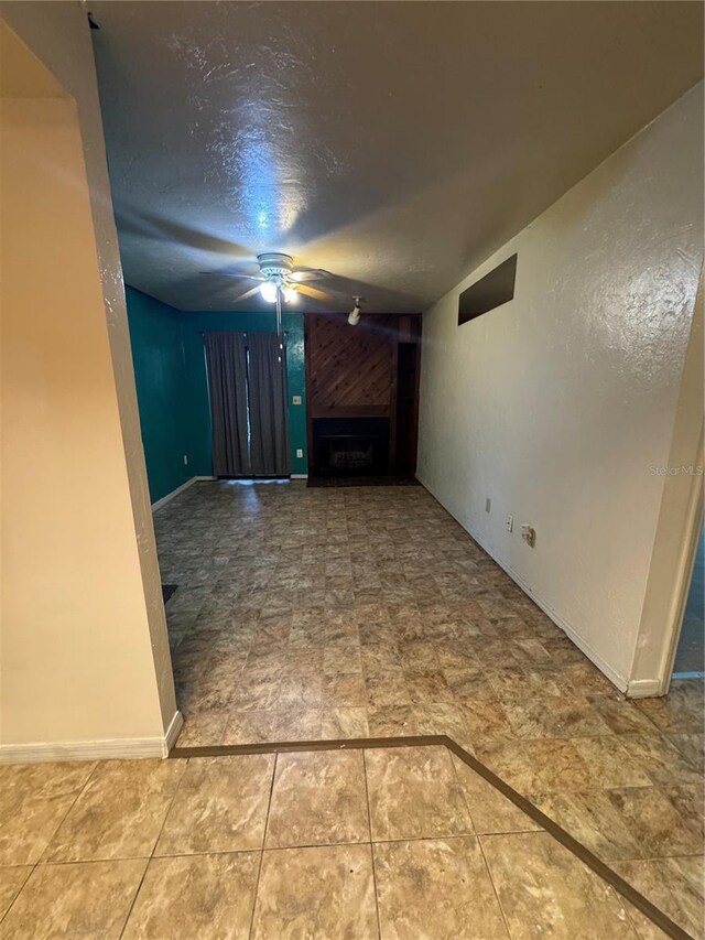 1515 NW 29th Rd Unit E3, Gainesville, FL 32605 - unfurnished living room with a fireplace, a ceiling fan, baseboards, and a textured ceiling