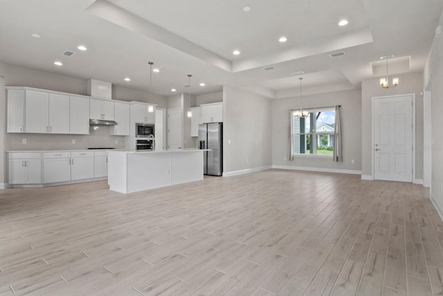 3520 SW 120th Dr, Gainesville, FL 32608 - kitchen with appliances with stainless steel finishes, a chandelier, a raised ceiling, open floor plan, and under cabinet range hood