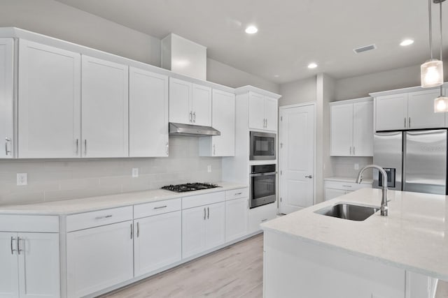 3520 SW 120th Dr, Gainesville, FL 32608 - kitchen featuring appliances with stainless steel finishes, under cabinet range hood, white cabinets, hanging light fixtures, and recessed lighting