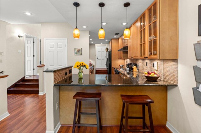 5328 NW 9th Ln, Gainesville, FL 32605 - kitchen featuring brown cabinets, freestanding refrigerator, under cabinet range hood, range, and dark wood-type flooring