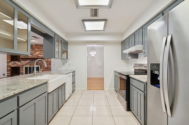 2626 NW 36th Pl, Gainesville, FL 32605 - kitchen with stainless steel appliances, under cabinet range hood, gray cabinets, light stone counters, and backsplash