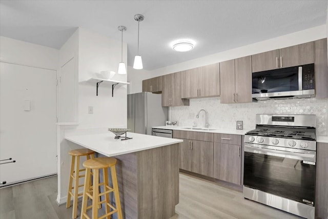 1700 SW 16th Ct Unit E30, Gainesville, FL 32608 - kitchen with stainless steel appliances, light wood finished floors, a kitchen bar, a peninsula, and decorative backsplash