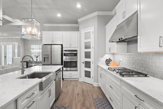 9474 SW 65th Pl, Gainesville, FL 32608 - kitchen featuring under cabinet range hood, stainless steel appliances, crown molding, a chandelier, and white cabinets