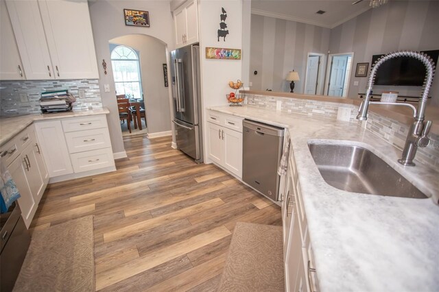 2361 Sandy Run Dr N, Middleburg, FL 32068 - kitchen with appliances with stainless steel finishes, arched walkways, white cabinetry, decorative backsplash, and light wood-type flooring