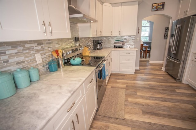 2361 Sandy Run Dr N, Middleburg, FL 32068 - kitchen featuring stainless steel appliances, extractor fan, arched walkways, light wood-style flooring, and white cabinetry