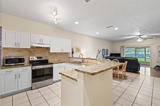 13200 W Newberry Rd Unit T110, Newberry, FL 32669 - kitchen featuring stainless steel appliances, under cabinet range hood, a peninsula, light tile patterned floors, and open floor plan