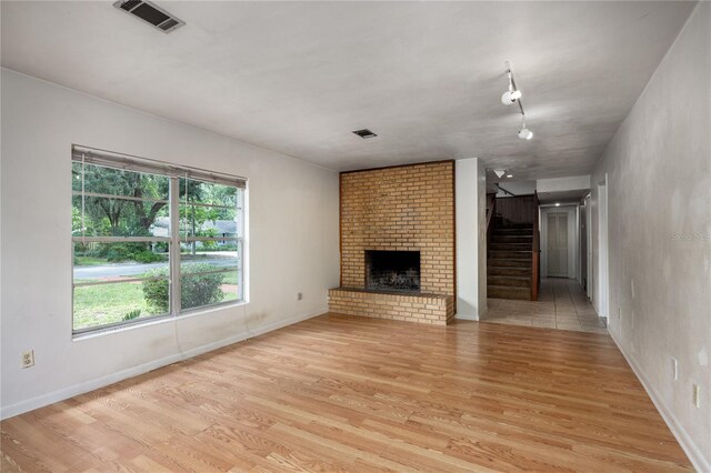 2147 NW 7th Pl, Gainesville, FL 32603 - unfurnished living room featuring light wood-style floors, stairway, and a fireplace