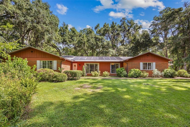 2809 SW 81st St, Gainesville, FL 32608 - ranch-style house with an attached garage, roof mounted solar panels, a front yard, and brick siding