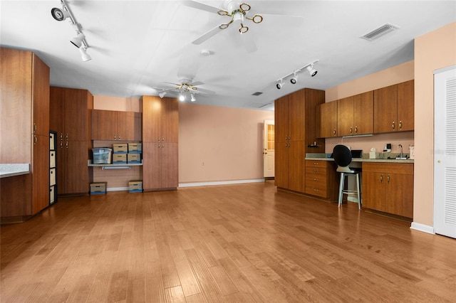 2809 SW 81st St, Gainesville, FL 32608 - kitchen featuring rail lighting, brown cabinetry, built in desk, light wood-type flooring, and ceiling fan