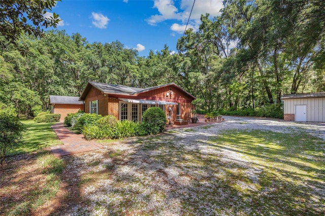 2809 SW 81st St, Gainesville, FL 32608 - view of side of home featuring brick siding, a lawn, a storage shed, and a view of trees