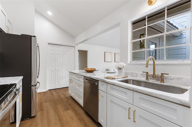 10943 NW 34th Pl, Gainesville, FL 32606 - kitchen with stainless steel appliances, lofted ceiling, wood finished floors, white cabinets, and light stone counters