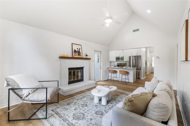 10943 NW 34th Pl, Gainesville, FL 32606 - living room featuring a ceiling fan, high vaulted ceiling, light wood-type flooring, and a brick fireplace