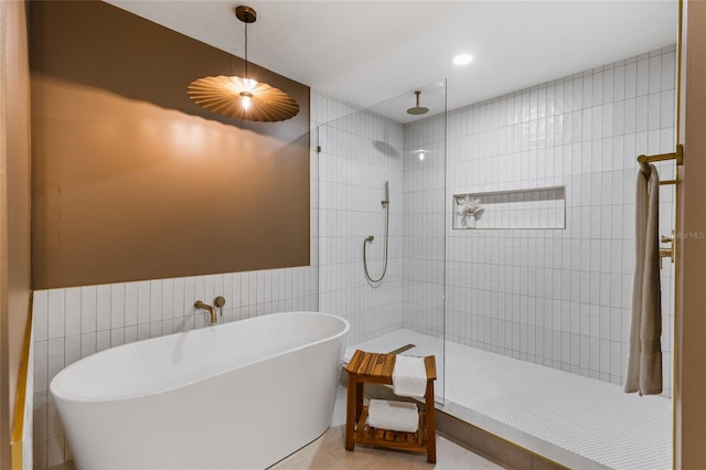 10943 NW 34th Pl, Gainesville, FL 32606 - full bath featuring tile walls, walk in shower, a soaking tub, tile patterned flooring, and a wainscoted wall