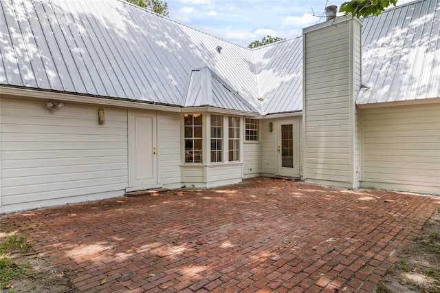10943 NW 34th Pl, Gainesville, FL 32606 - back of house featuring a metal roof, a chimney, and a patio area