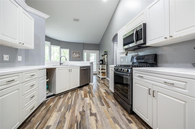 9911 NW 24th Pl, Gainesville, FL 32606 - kitchen featuring stainless steel appliances, vaulted ceiling, wood finished floors, white cabinets, and light countertops