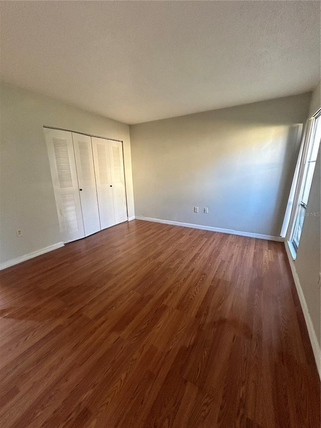 2811 SW Archer Rd Unit X203, Gainesville, FL 32608 - unfurnished bedroom featuring dark wood-type flooring, a closet, and a textured ceiling