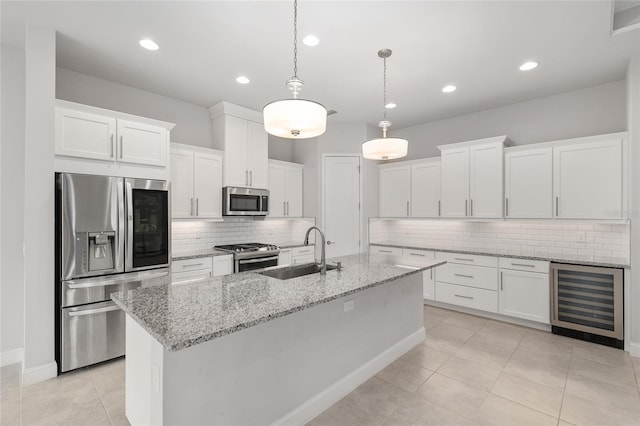 11890 SW 33rd Ln, Gainesville, FL 32608 - kitchen featuring wine cooler, appliances with stainless steel finishes, tasteful backsplash, a kitchen island with sink, and white cabinets