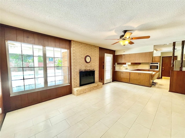 2268 NW 17th Ave, Gainesville, FL 32605 - unfurnished living room featuring wood walls, a ceiling fan, a textured ceiling, and a fireplace