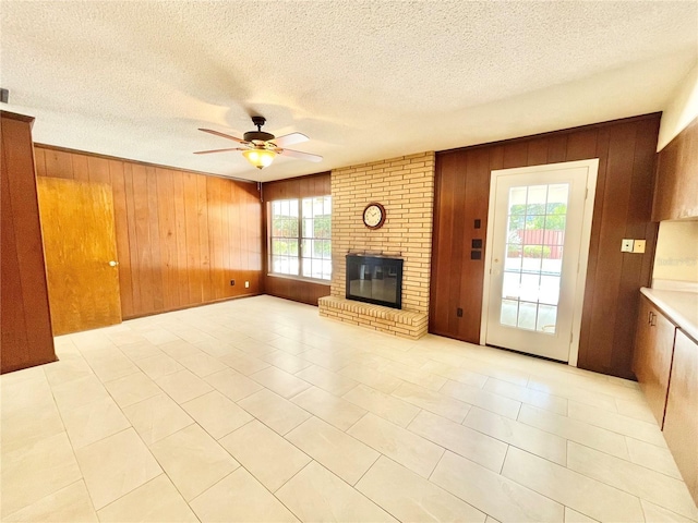 2268 NW 17th Ave, Gainesville, FL 32605 - unfurnished living room with wooden walls, healthy amount of natural light, ceiling fan, a brick fireplace, and light tile patterned flooring