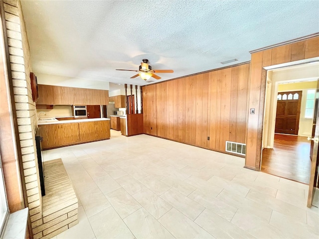 2268 NW 17th Ave, Gainesville, FL 32605 - unfurnished living room with ceiling fan, wood walls, and a textured ceiling