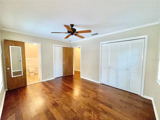 2268 NW 17th Ave, Gainesville, FL 32605 - unfurnished bedroom featuring wood finished floors, ornamental molding, two closets, connected bathroom, and a ceiling fan