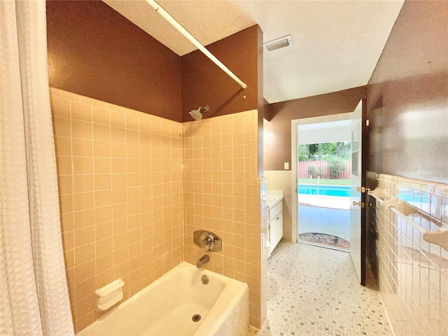 2268 NW 17th Ave, Gainesville, FL 32605 - bathroom featuring shower / bath combination, tile walls, wainscoting, vanity, and tile patterned floors