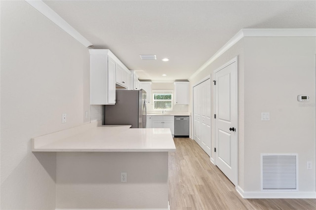9011 N Travis Dr, Citrus Springs, FL 34434 - kitchen featuring stainless steel appliances, white cabinetry, crown molding, light wood-style flooring, and light countertops