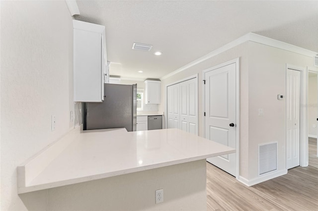 9011 N Travis Dr, Citrus Springs, FL 34434 - kitchen with appliances with stainless steel finishes, a peninsula, white cabinetry, light countertops, and light wood-style flooring