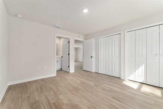 9011 N Travis Dr, Citrus Springs, FL 34434 - unfurnished bedroom featuring multiple closets, light wood-style flooring, and recessed lighting