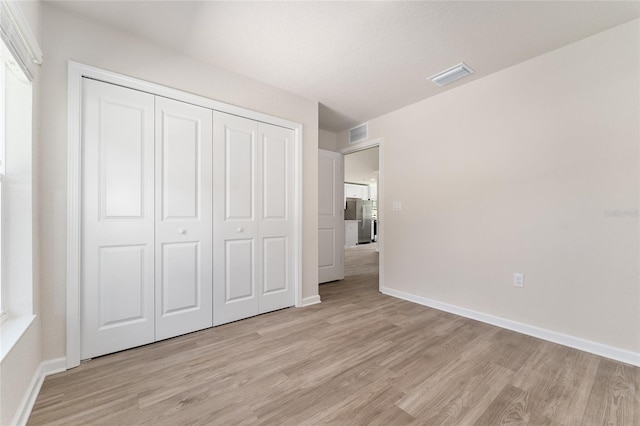 9011 N Travis Dr, Citrus Springs, FL 34434 - unfurnished bedroom with light wood-style flooring, freestanding refrigerator, and a closet