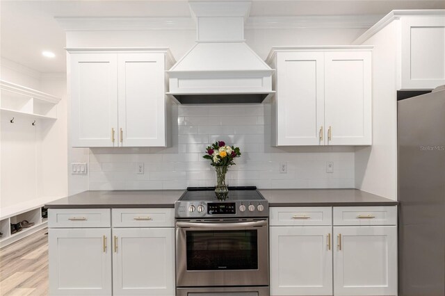 1425 SW 67th Dr, Gainesville, FL 32607 - kitchen with stainless steel appliances, custom range hood, crown molding, dark countertops, and white cabinetry