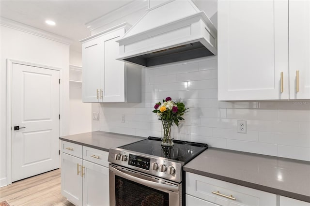 1425 SW 67th Dr, Gainesville, FL 32607 - kitchen with stainless steel electric range, custom exhaust hood, dark countertops, white cabinetry, and crown molding