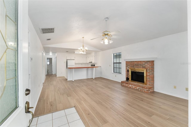 2963 SW 40th Ave, Gainesville, FL 32608 - unfurnished living room featuring vaulted ceiling, ceiling fan, a chandelier, light wood-type flooring, and a brick fireplace