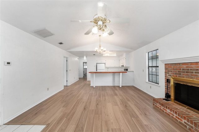 2963 SW 40th Ave, Gainesville, FL 32608 - unfurnished living room featuring a ceiling fan, vaulted ceiling, light wood finished floors, a fireplace, and a chandelier