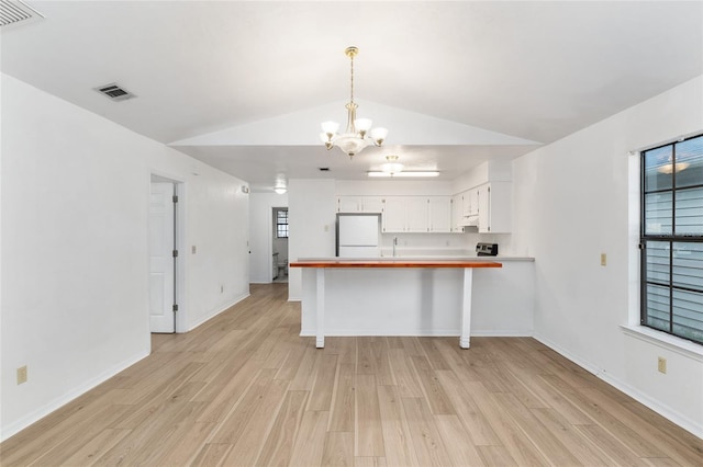 2963 SW 40th Ave, Gainesville, FL 32608 - kitchen with white fridge, a chandelier, light wood finished floors, lofted ceiling, and a peninsula