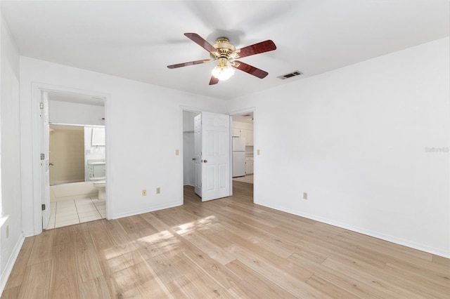 2963 SW 40th Ave, Gainesville, FL 32608 - unfurnished bedroom with freestanding refrigerator, light wood-style flooring, connected bathroom, a walk in closet, and ceiling fan