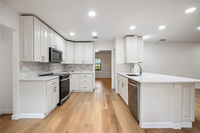 820 NW 109th Dr, Gainesville, FL 32606 - kitchen with stainless steel appliances, a peninsula, decorative backsplash, light wood-style floors, and white cabinets