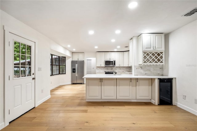820 NW 109th Dr, Gainesville, FL 32606 - kitchen featuring stainless steel appliances, beverage cooler, a peninsula, decorative backsplash, and light countertops
