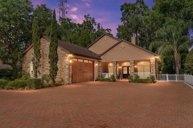 552 NW 136th St, Newberry, FL 32669 - view of front of house featuring a garage, a porch, stone siding, and decorative driveway